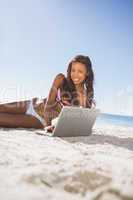 Cheerful attractive woman in bikini using her computer