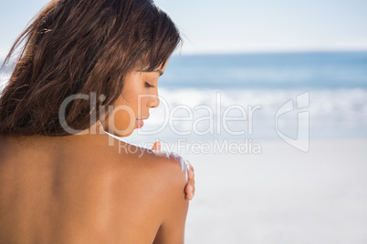 Relaxed woman applying sun cream on her shoulder