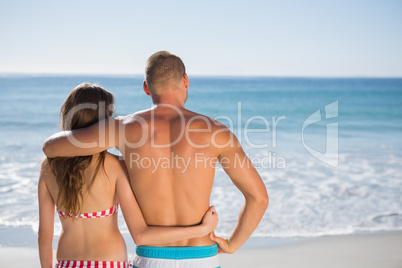 Loving couple embracing one another while looking at the sea