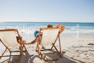 Cute couple lying on their deck chairs