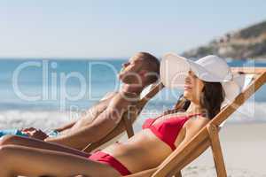 Young couple on their deck chairs having a nap
