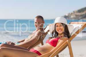 Young couple on their deck chairs smiling at camera