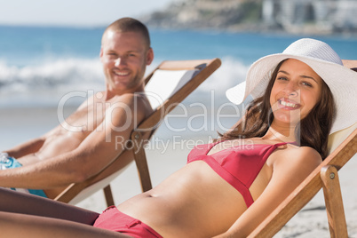 Cheerful couple on their deck chairs smiling at camera
