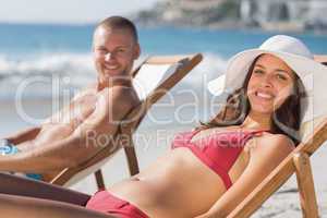 Cheerful couple on their deck chairs smiling at camera