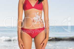Slim woman body with sun cream on belly