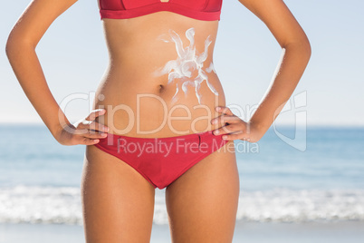 Fit woman body with sun cream on belly