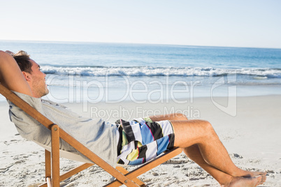Handsome man lying on his deck chair admiring sea