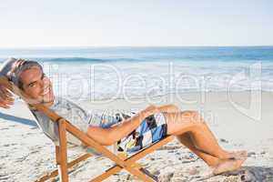 Handsome man lying on his deck chair smiling at camera