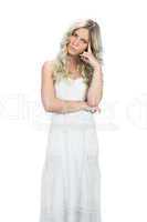 Frowning attractive model in white dress posing touching her hea