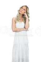 Pensive attractive model in white dress posing touching her head