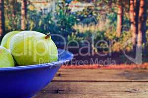 Bowl of fresh figs on rustic wooden table against forest backgro