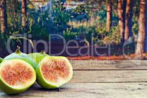 Fresh figs on rustic wooden table against forest background