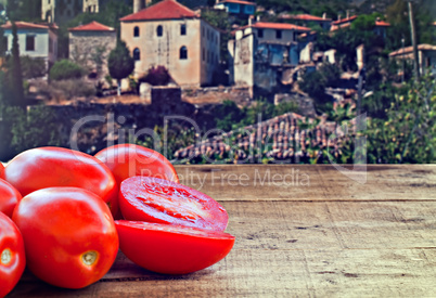 Fresh plum tomatoes on rustic wooden table with old countryside