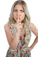 Frowning blond model  wearing flowered dress hiding secret