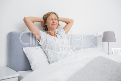 Blonde woman stretching and smiling in bed