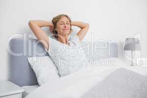 Blonde woman stretching and smiling in bed