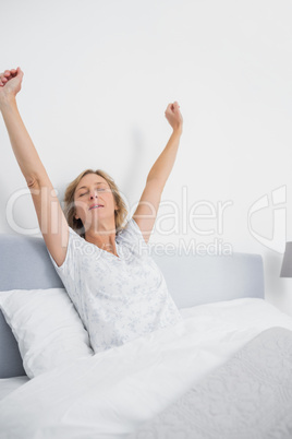 Blonde woman stretching in bed in the morning