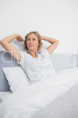 Blonde woman stretching and looking away in bed in the morning