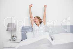 Well rested blonde woman stretching after waking up in bed
