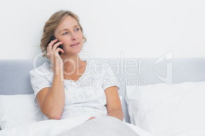 Blonde woman on the phone in bed