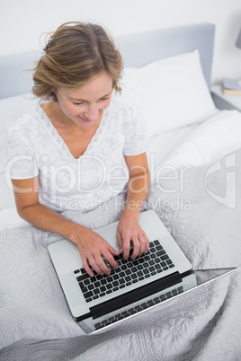 Content blonde woman in bed using her laptop