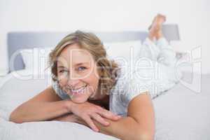 Happy blonde woman lying on bed