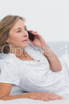 Blonde woman lying on bed making a phone call