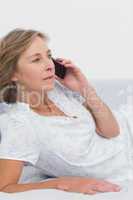 Blonde woman lying on bed making a phone call