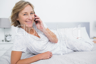 Relaxed blonde woman lying on bed making a phone call