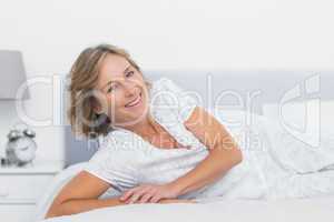 Cheerful blonde woman lying on bed