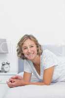 Happy blonde woman lying on bed