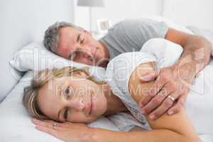 Woman smiling at camera as husband is sleeping