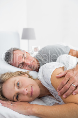 Blonde woman smiling at camera as husband is sleeping