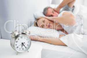 Couple covering their ears from alarm clock noise