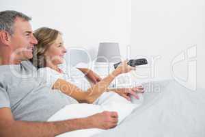 Content couple cuddling in bed watching television