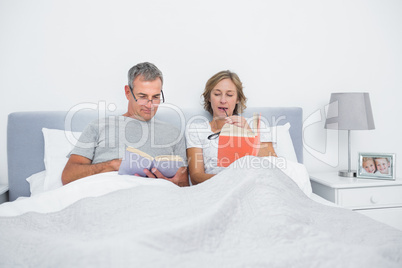 Happy couple sitting in bed reading books