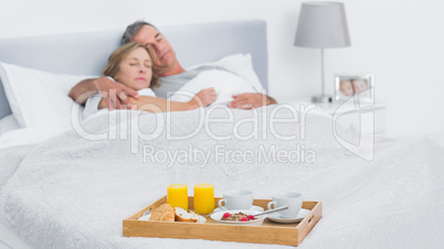 Couple sleeping with breakfast tray on bed