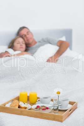 Peaceful couple sleeping with breakfast tray on bed