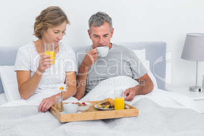 Happy couple having breakfast in bed together