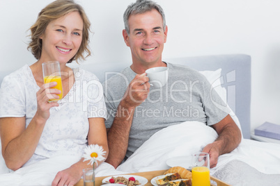 Cheerful couple having breakfast in bed together