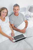 Couple using their laptop together in bed