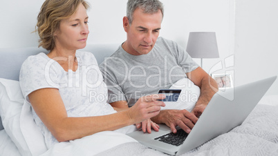 Thoughtful couple using their laptop to buy online
