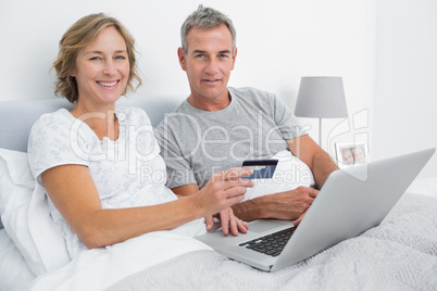Smiling couple using their laptop to buy online