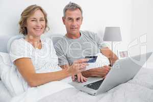 Smiling couple using their laptop to buy online