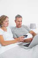 Cheerful couple using their laptop to buy online