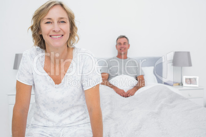Happy couple sitting on opposite ends of bed