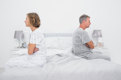 Couple sitting on different sides of bed not talking after dispu