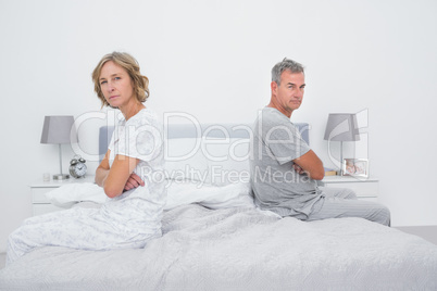 Couple sitting on different sides of bed not talking after argum