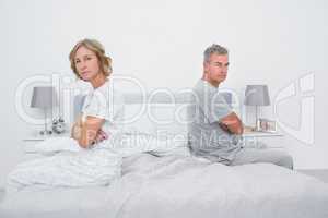 Couple sitting on different sides of bed not talking after argum
