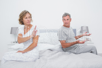 Couple sitting on different sides of bed having an argument